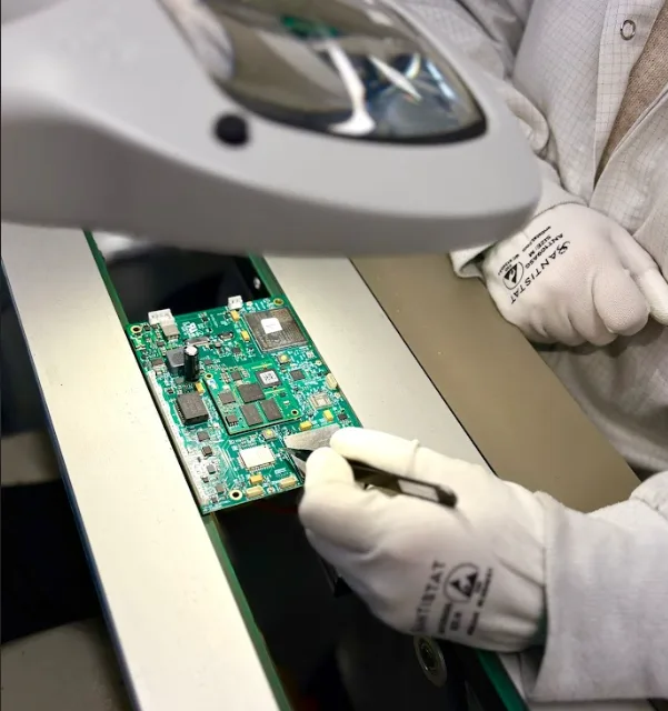 Operateur TERA Tronics inspectant une carte electronique sous loupe en environnement ESD